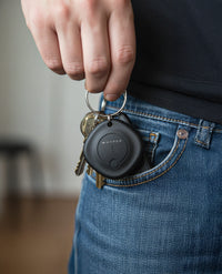 Person holding a keychain with a black device labeled 'Hyper' against a blurred background.