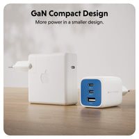 Two compact wall chargers shown on a wooden surface against a soft light background. The larger charger in back is white with an Apple logo, and the smaller charger in front is white with a blue front panel and USB-C ports.